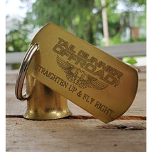 Load image into Gallery viewer, Brass bell made of a .50 cal shell with brass tag that says &quot;Straighten Up &amp; Fly Right&quot;
