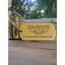 Load image into Gallery viewer, brass bell made of a .50 cal shell with brass tag that says &quot;Fun begins where pavement ends&quot;
